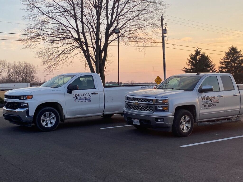 Wilkes and DeLuca service pickup trucks in the company lot at sunset