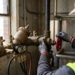 Technician testing a reduced-pressure backflow preventer with a differential pressure test kit